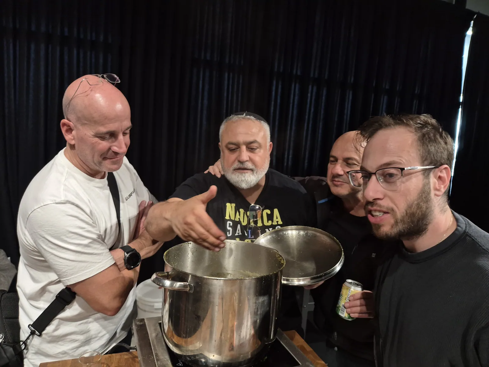 צוות צוחק סביב סיר הבישול בסדנה במשרד