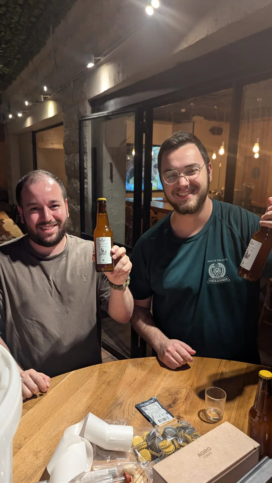 שני משתתפים מרימים בקבוק בירה ומחייכים